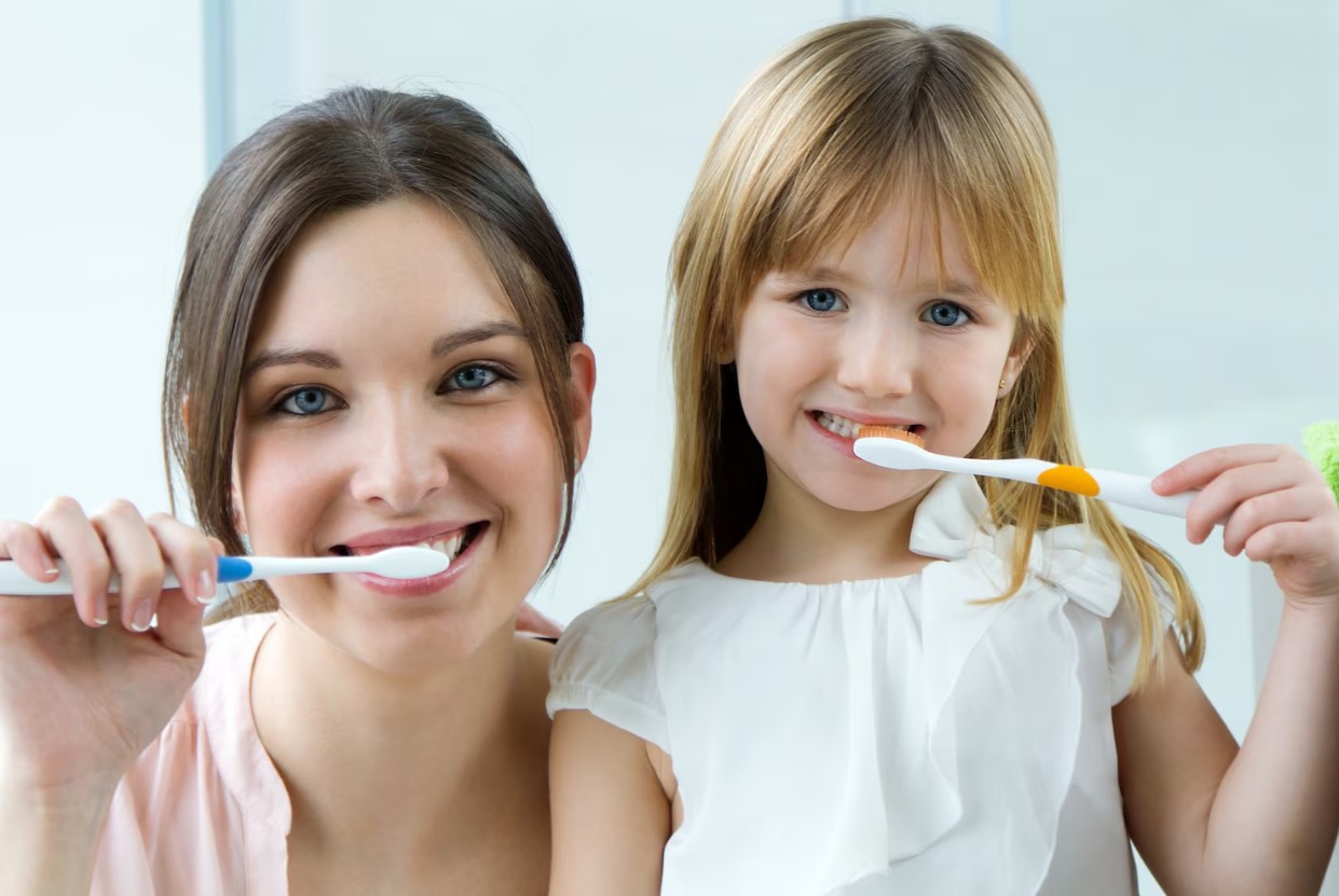 Mother and daughter smiling while brushing teeth, promoting oral hygiene and family dental care at Laguna Niguel Dental.